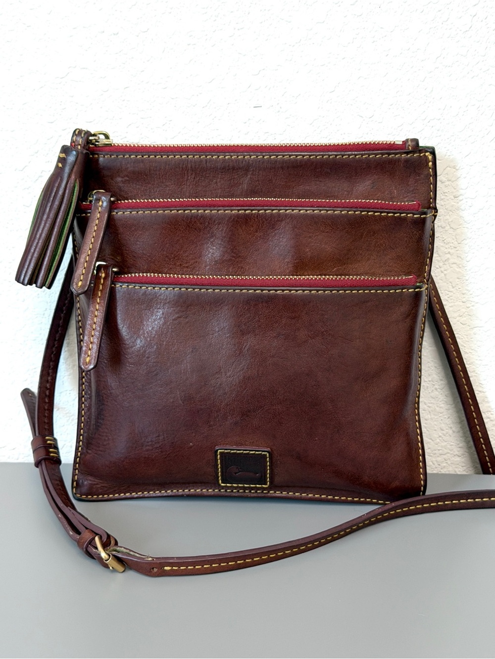 Dooney & Bourke Florentine leather triple zip crossbody bag in a chestnut brown